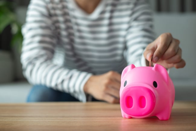 a-young-employee-is-putting-coins-into-a-pink-piggy-bank-and-recording-income-and-expenses-on-the-desk-he-saved-his-friends-money-to-invest-in-the-fu-1