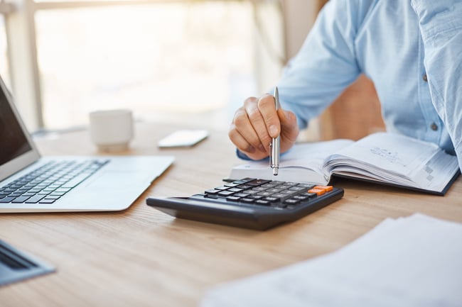 close-up-detail-of-professional-serious-accountant-sitting-in-light-office-checking-company-finance-profits-on-calculator-scaled