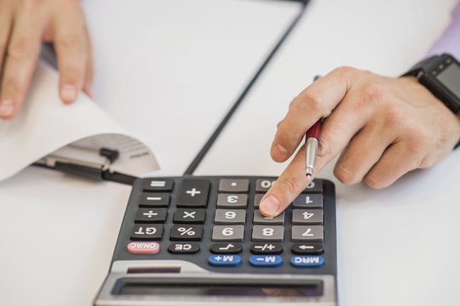 close-up-of-businessman-calculating-invoices-using-calculator-scaled