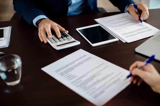 closeup-of-financial-consultant-going-through-paperwork-on-a-meeting-with-a-client-scaled