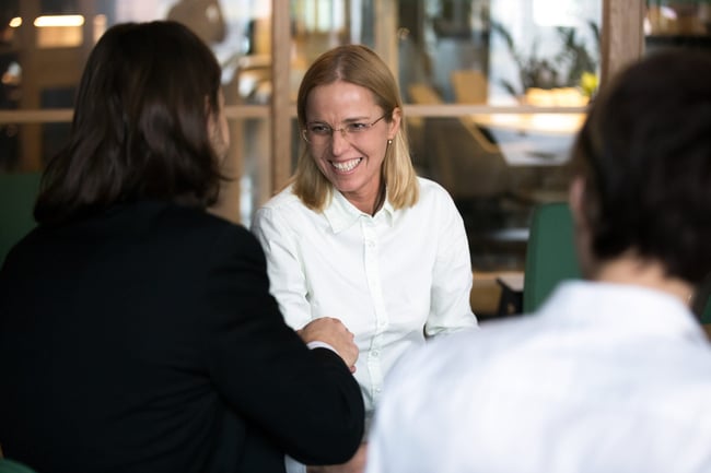smiling-businesswoman-shaking-hand-of-businessman-at-negotiations-or-interview-scaled