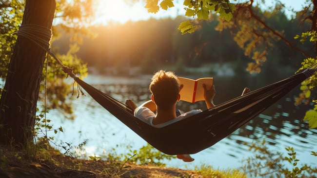 young-man-relaxing-hammock-reading-book-sun-is-setting-lake-background-scaled