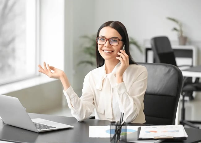pani siedzi przy biurku i rozmawia przez telefon