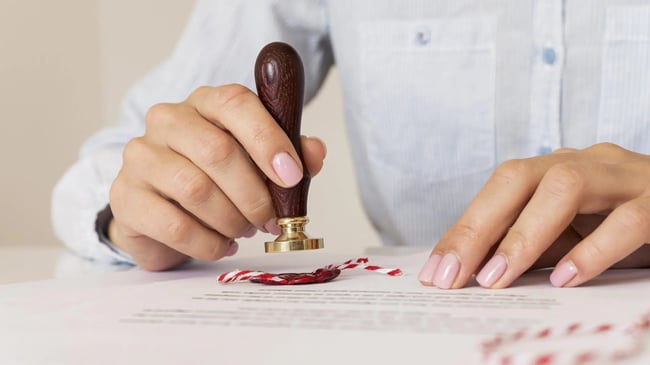 person-using-a-wax-seal-blurred-certificate-scaled