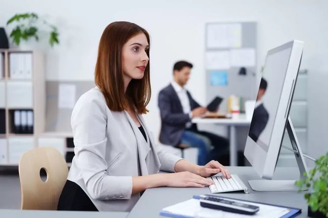 kobieta pisze na klawiaturze przed monitorem