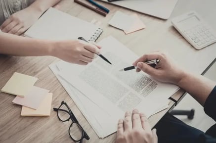 dwie osoby wypełniają dokumenty na biurku