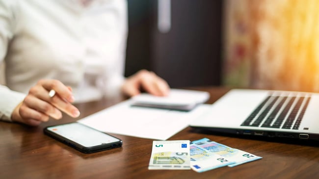 woman-working-with-finances-on-the-table-laptop-smartphone-money-notepad-scaled