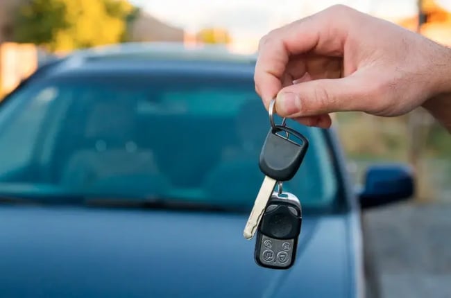 ręka trzyma kluczyki do auta przed pojazdem