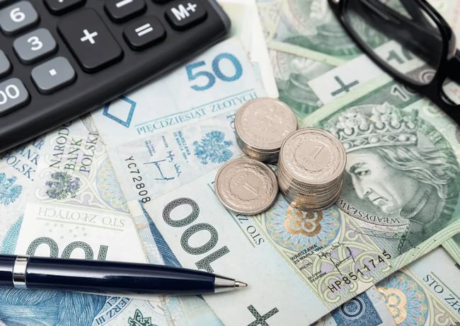 Polskie banknoty i monety leżą obok kalkulatora