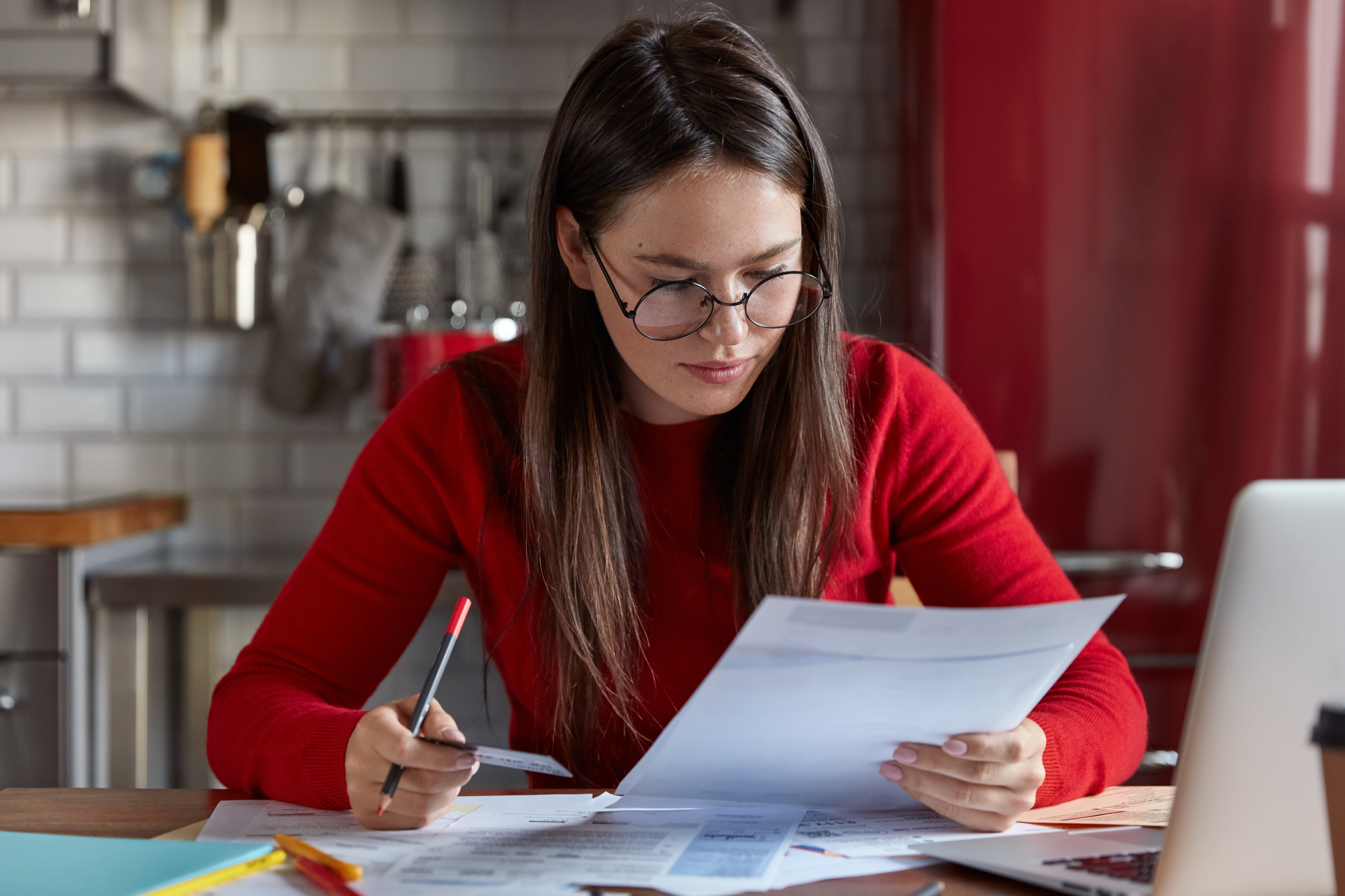 indoor-shot-of-woman-in-optical-glasses-checks-bank-account-recieves-bills-holds-plastic-card