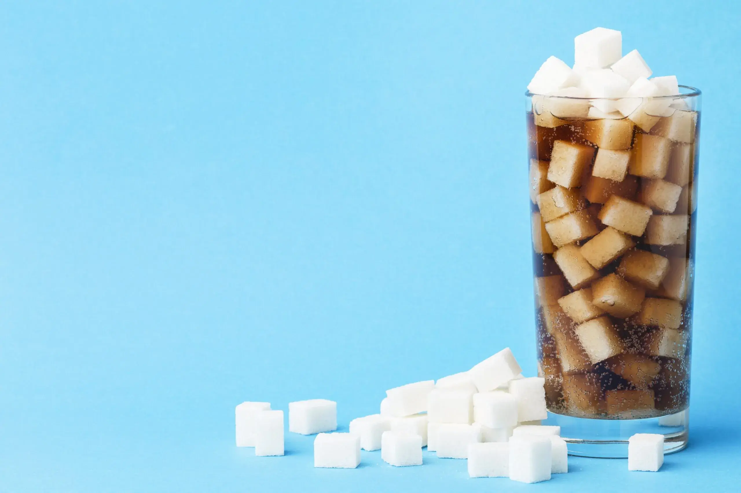 front-view-of-glass-of-soft-drink-with-sugar-cubes-and-copy-space-scaled