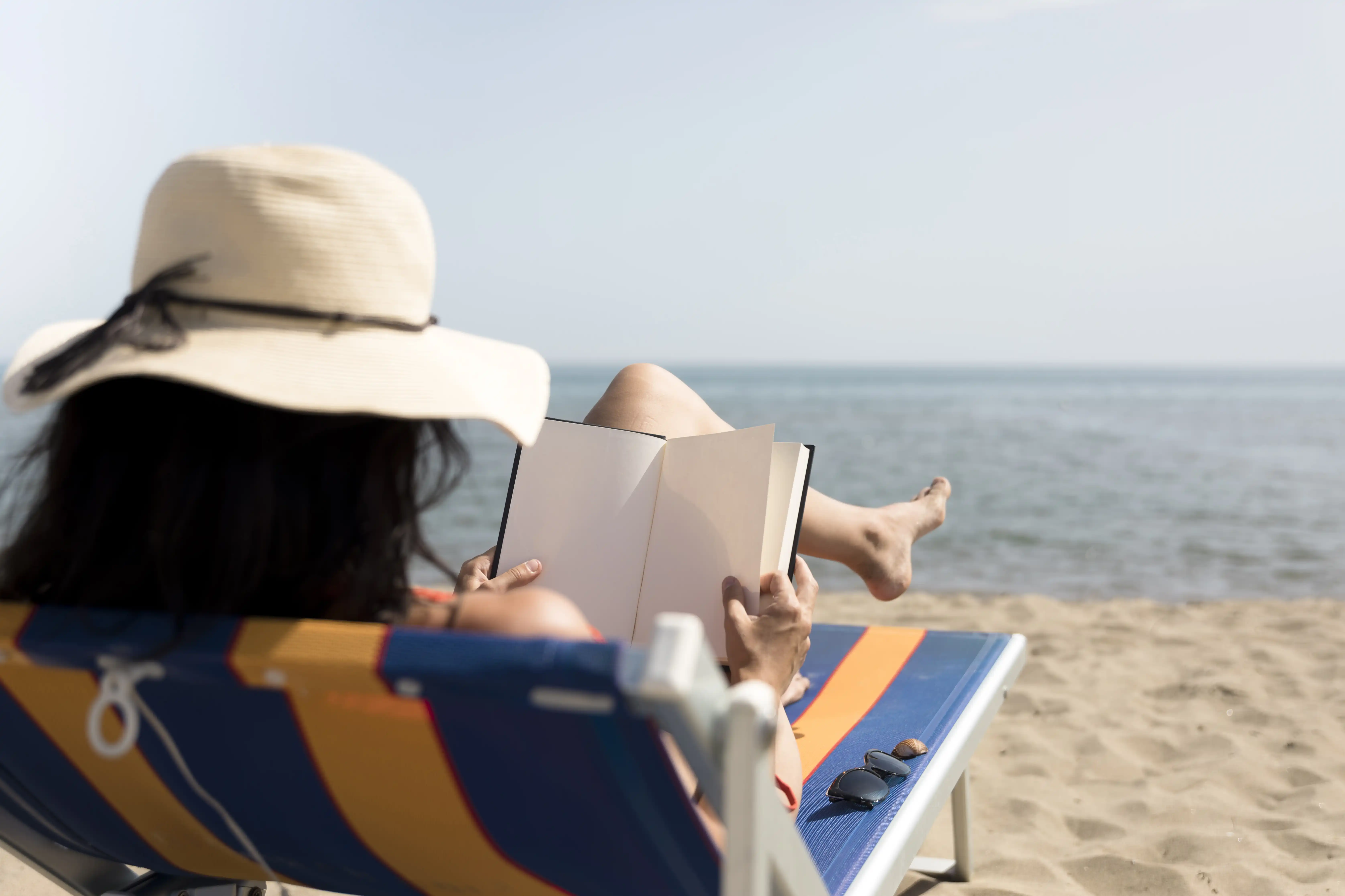 kobieta na plaży czyta na leżaku