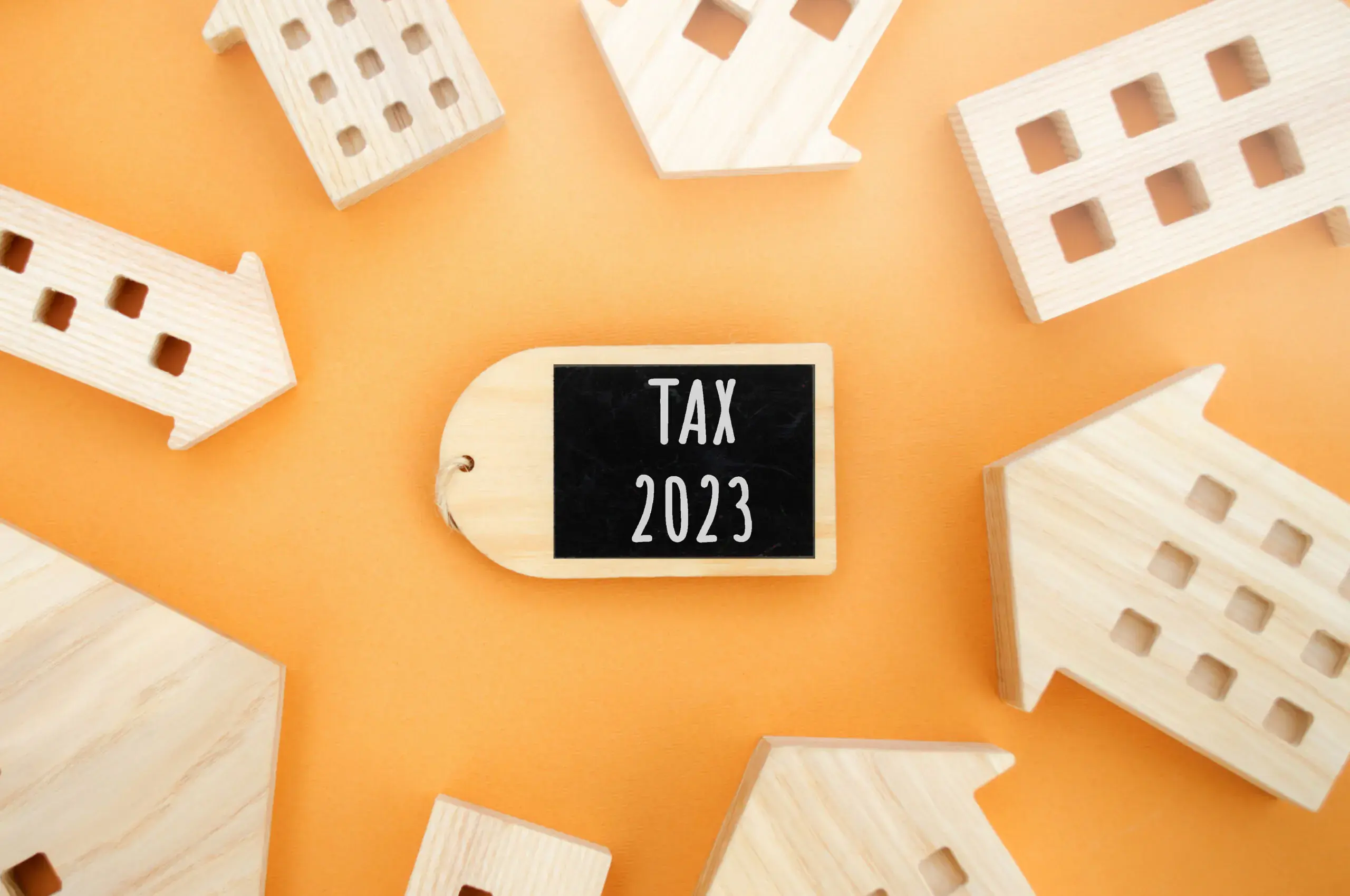 wooden-houses-and-the-inscription-between-them-tax-2023-real-estate-and-housing-taxes-concept-business-and-finance-taxation-money-savings-scaled
